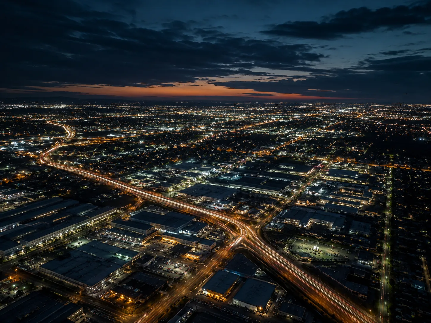Aerial night view across Melbourne’s south-east with illuminated arterial roads, industrial precincts and suburban streets