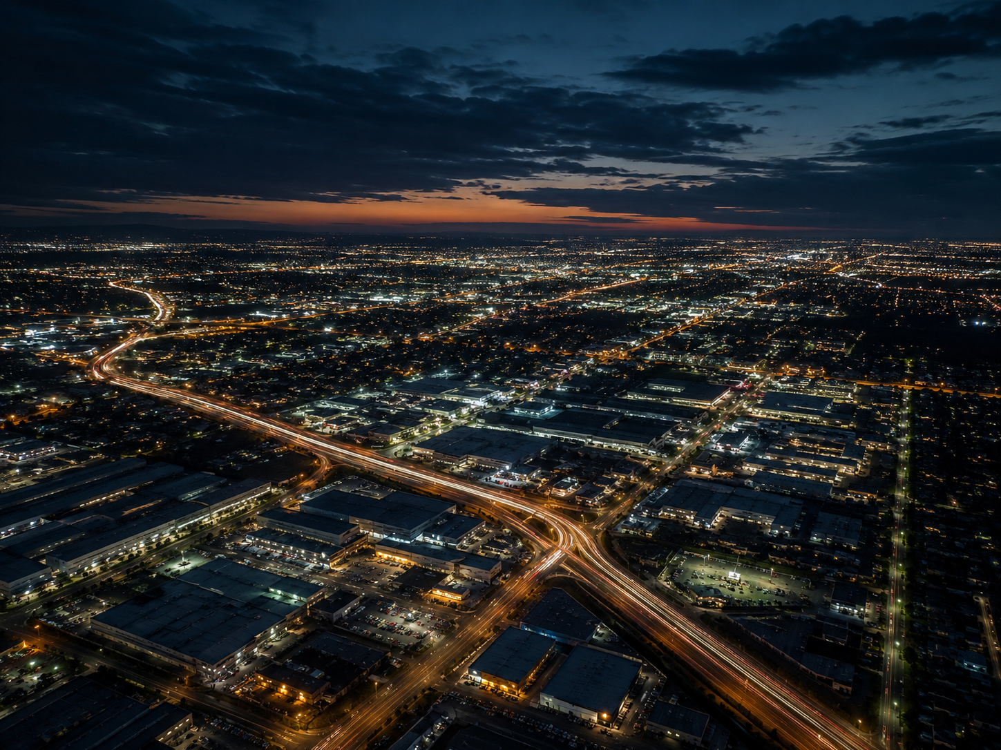 Aerial night view across Melbourne’s south-east with illuminated arterial roads, industrial precincts and suburban streets